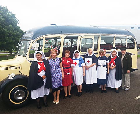 Members in vintage dress with vintage bus marking 65 years of the NHS
