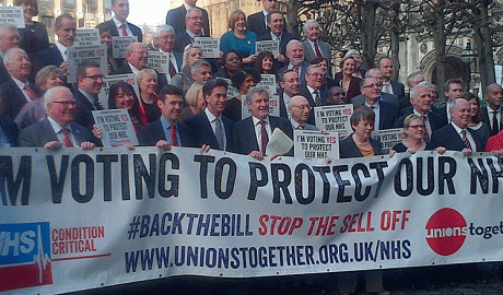 MPs stand with a banner saying 'I'm voting to protect the NHS'