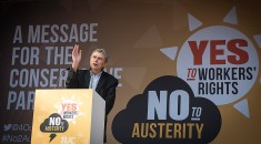 Dave Prentis on stage at the Manchester rally with backdrop reading Yes to workers' rights, No to austerity