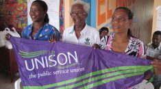 Three women from Columbia holding a UNISON flag