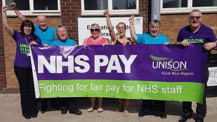 Members standing with banner reading: NHS pay – fighting for fair pay for NHS staff