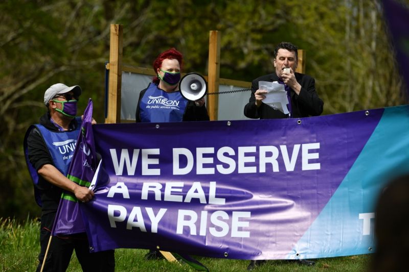 UNISON members with megaphone standing behind banner that says 'we deserve a real pay rise'