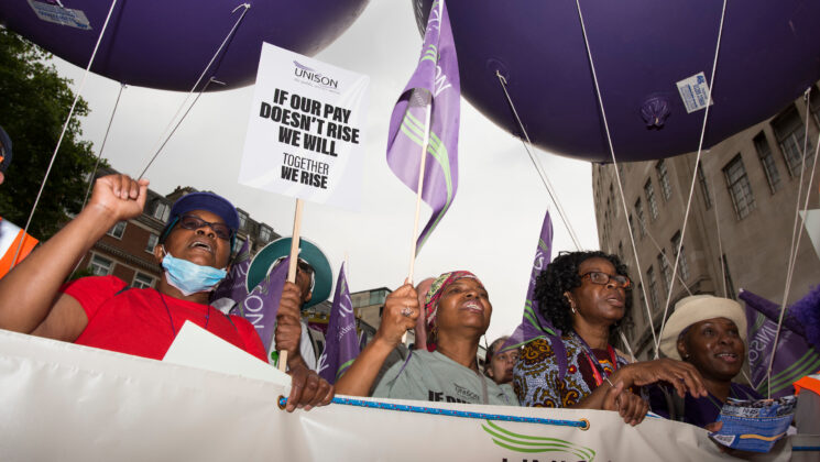 Four UNISON members carrying a banner march through the streets of London