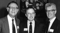 Black and white photo of Alan Jinkinson, then general secretary of NALGO, Hector MacKenzie, then general secretary of COHSE, and Rodney Bickerstaffe, then general secretary of NUPE, against the COHSE trade union banner, at the 1990 COHSE conference