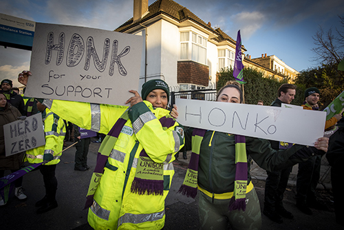 Pickets at Deptford holding handwritten signs calling on passing drivers to honk their support