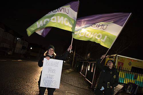pickets with UNISON flags and a 'honk for the NHS' placard