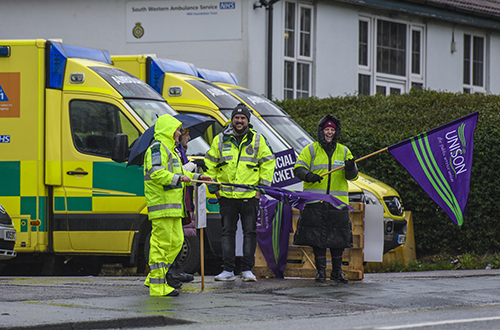 Pickets with two ambulances behind them, in the rain