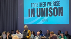 Top table at Higher Education Conference 2020 in Newcastle, a speaker is speaking in front of a 'Together we rise in UNISON' graphic