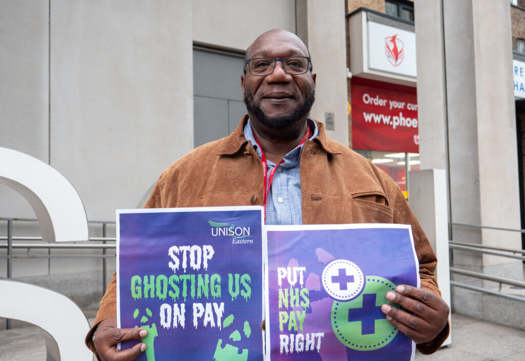 Glen Carrington, UNISON member and ambulance paramedic, holds placards saying: "stop ghosting us on pay" and "Put NHS Pay Right"