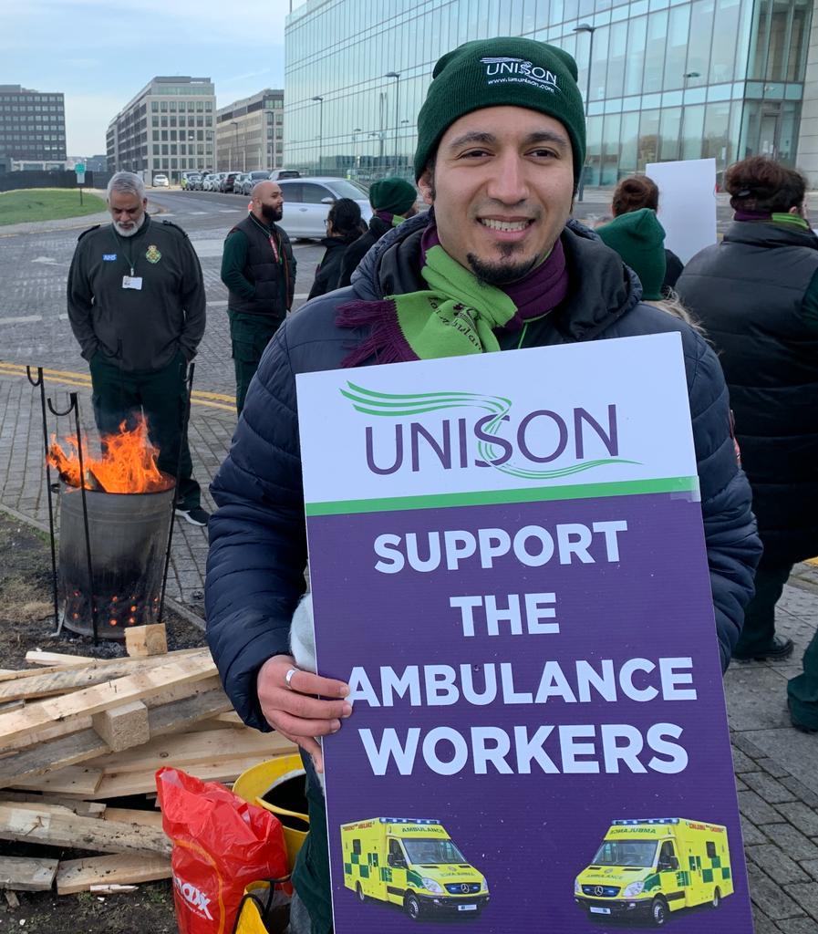 UNISON ambulance striker holding a "support the ambulance workers" in front of a brazier