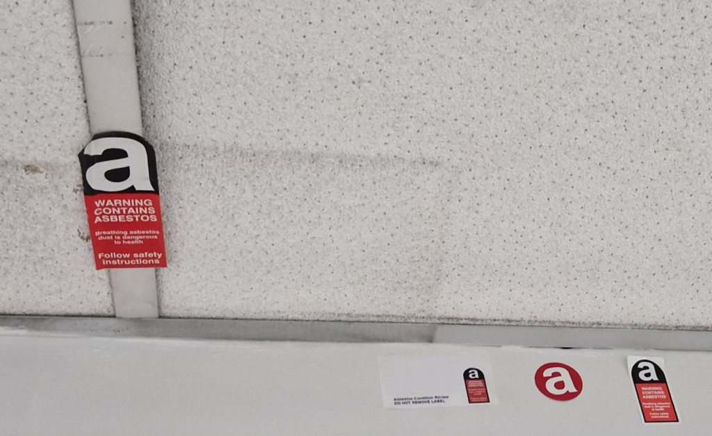 Image of suspended ceiling with asbestos warnings