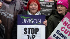 Andrea Egan holds placard at protest that reads 'stop the cuts'