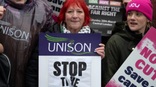Andrea Egan holds placard at protest that reads 'stop the cuts'