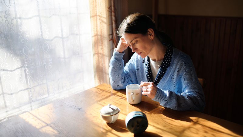 A woman sitting at a dining table looking concerned
